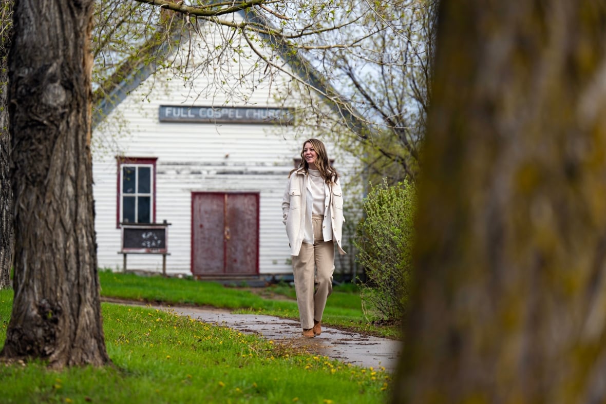 A woman walks in front of a small church.