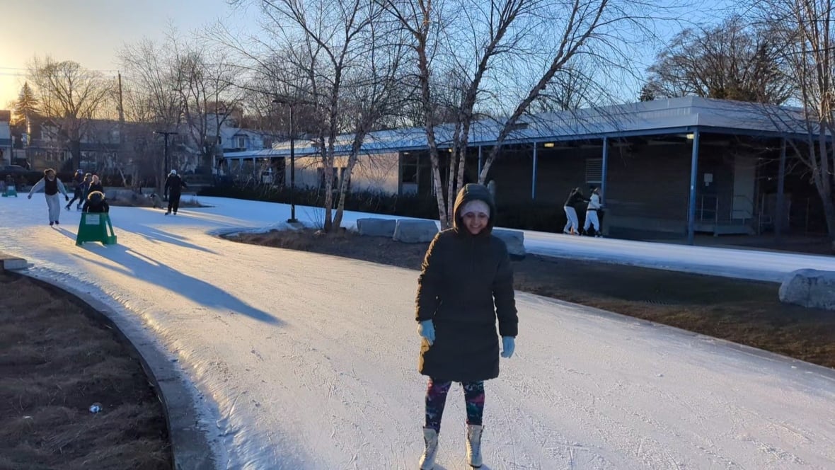 A woman dressed in winter clothing stands on ice skates.
